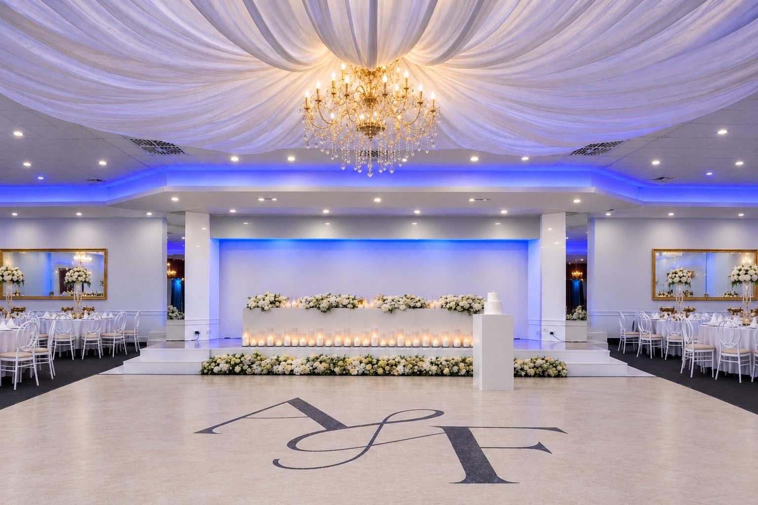 Emporium ballroom with a white draped ceiling, gold crystal chandelier and candlelit floral head table