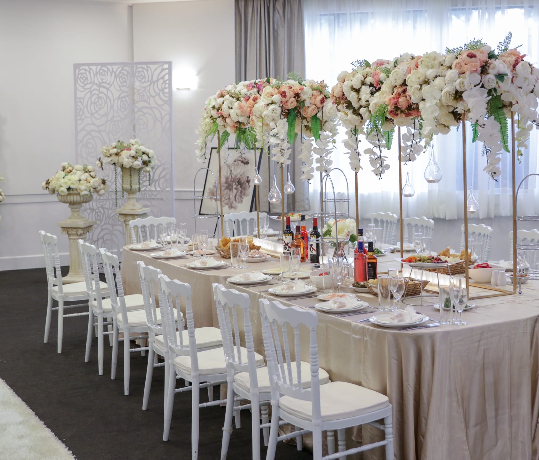 Long reception table beneath tall floral arrangements