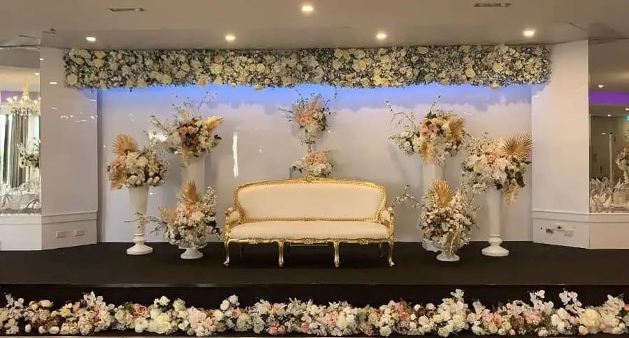 Gold-trimmed lounge on the stage beneath a floral wall