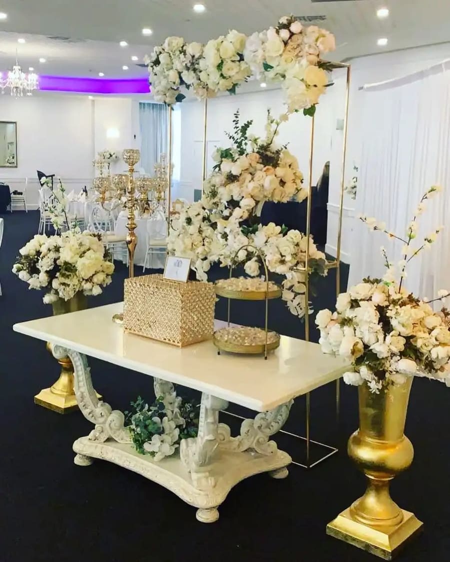 Gift table under a white floral arch, with gold candelabras