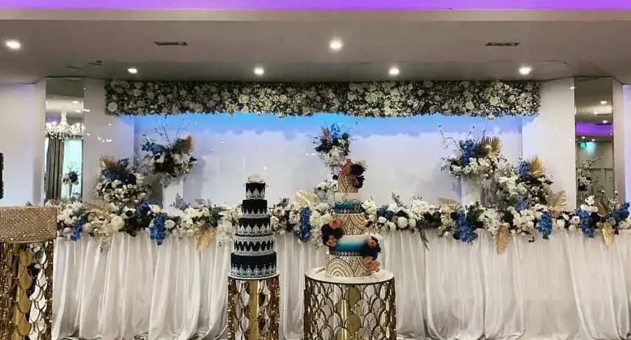 Two patterned tiered cakes in front of a blue and white floral head table
