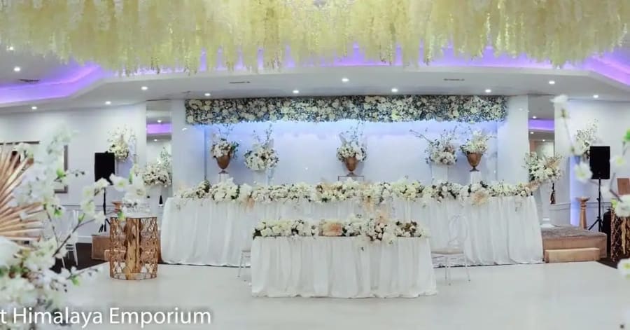 Head table under a white floral wall and hanging wisteria