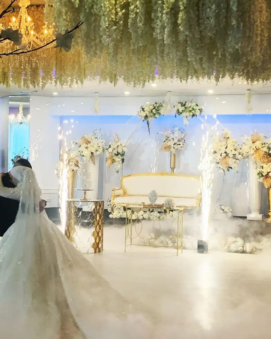 Bride and groom dancing as cold sparklers fire beside a gold lounge
