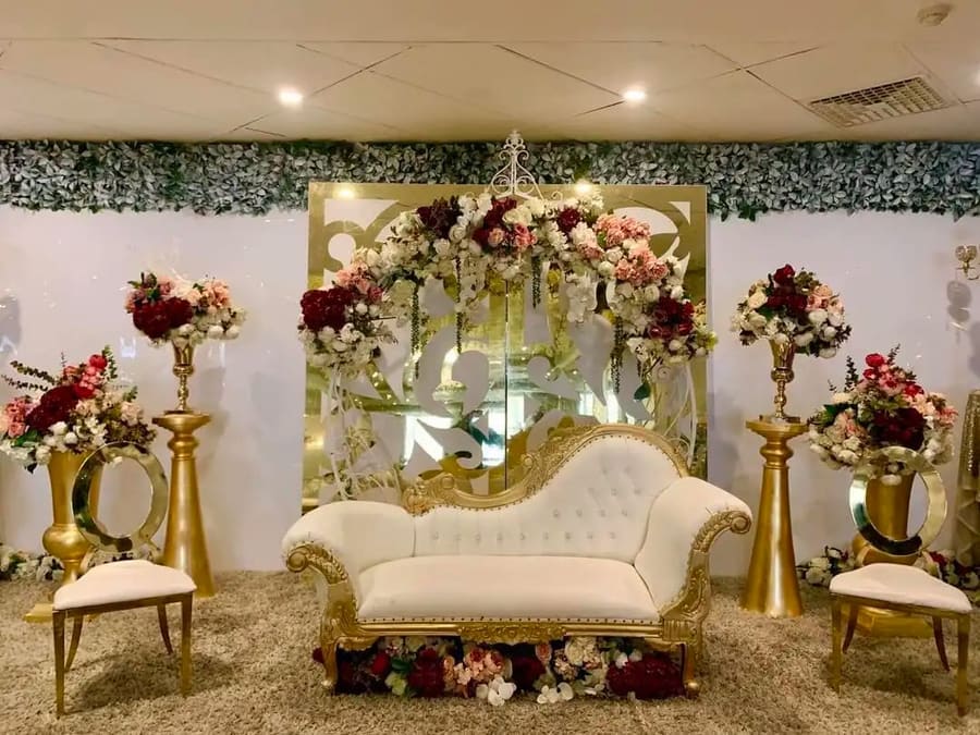White and gold lounge on a carpeted stage with red and white florals