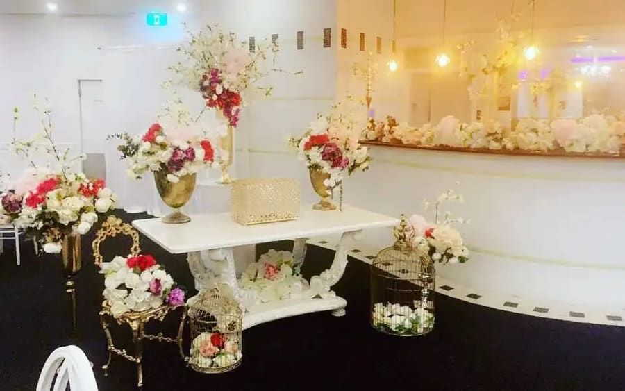 Gift table with birdcages and red and white florals in gold vases