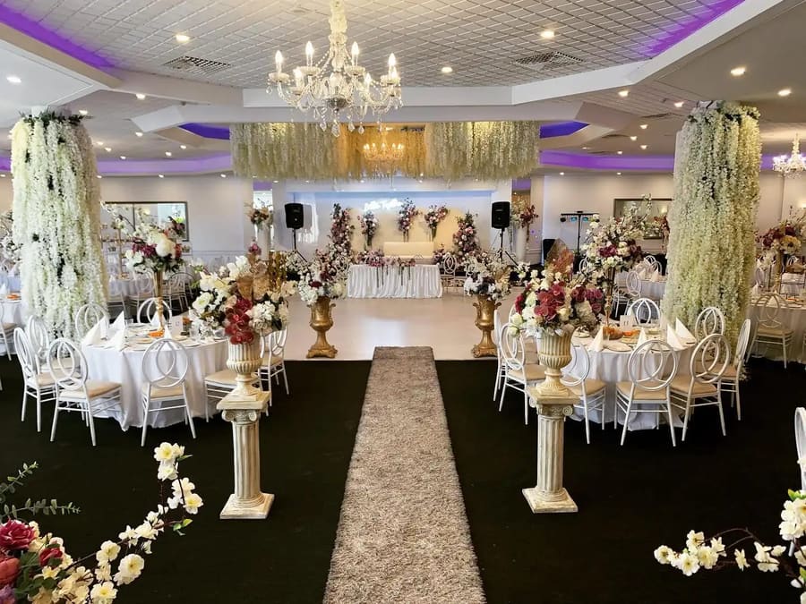 Aisle runner between floral pillars to the head table, round tables either side